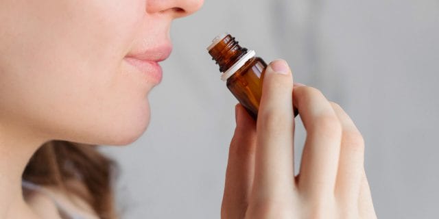 Person smelling a vial of essential oils for smell loss