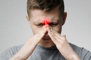 man holding nose because of sinus pain