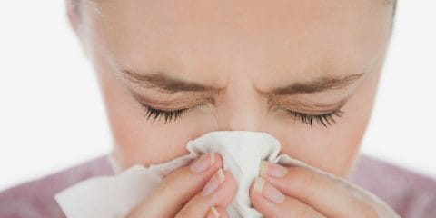Woman blowing nose because of allergies