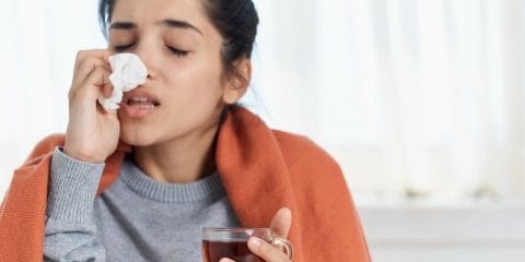 Woman with sinus infection holding tissue up to nose