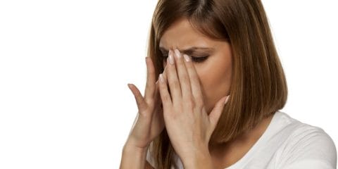 Woman with cystic fibrosis sinusitis and sinus headache holding her nose